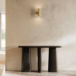 Minimalist Cylindrical Up Down Wall Light natural brass finish over a bench