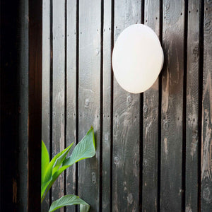 modern white round wall light hanging on a wooden wall outdoor